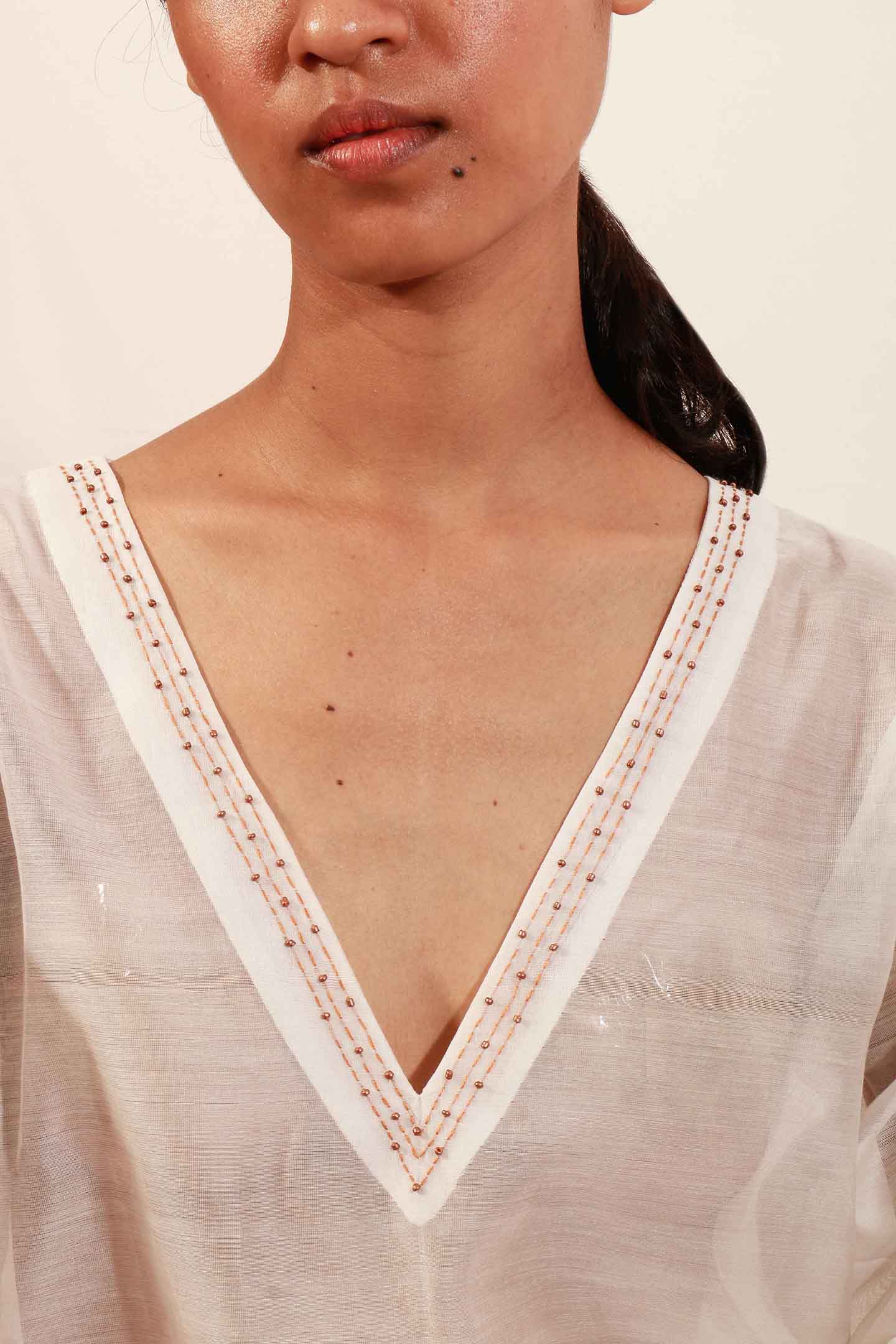 “V” Neck off-white translucent chanderi silk top with handcrafted embroidery and beadwork detail for women.