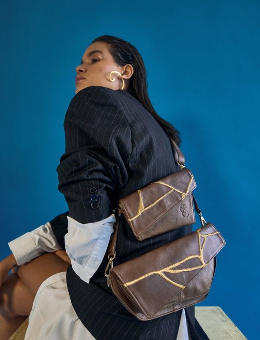 Brown handcrafted adjustable upcycled leather sling bag with gold embroidery.